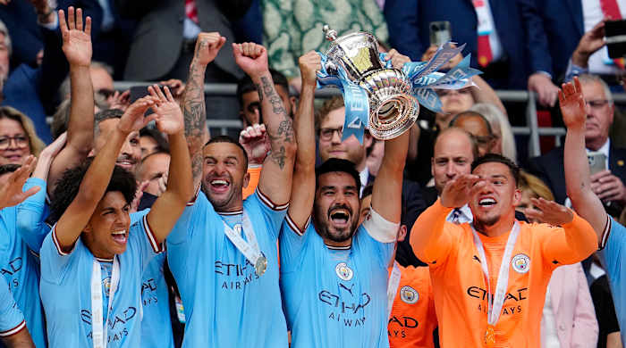Manchester City's Ilkay Gundogan raises the trophy after his team won the English FA Cup.